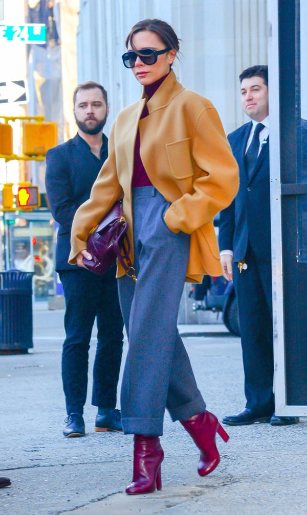 Виктория Бекхэм в широких брюках, пиджак горчичного цвета, бордовая водолазка, споги и сумка